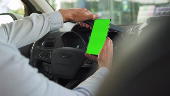 Driver Using a Smartphone Inside the Car. Chromakey Smartphone with Green Screen. Auto Navigation