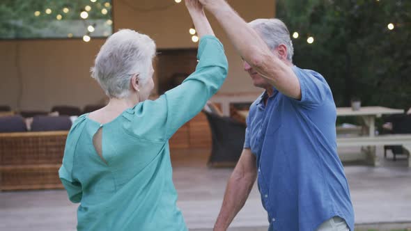 Senior Caucasian couple dancing and smiling in the garden