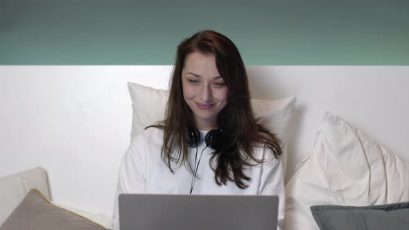 Beautiful Attractive Caucasian Woman with Long Hair in Bed Working on a Laptop