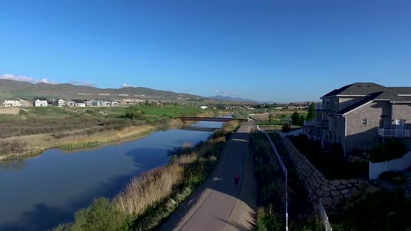 Aerial view of a river and trail with a jogger below and a golf course in the distance