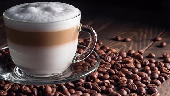 Cup with hot cappuccino drink on roasted coffee beans. dolly shot