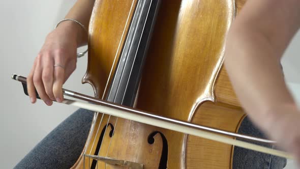 Girl Bows the Cello Strings To Play a Lyrical Composition. Close Up.