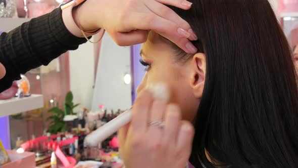 A Professional Makeup Artist Applies Make Up with a Special Brush in a Makeup Studio