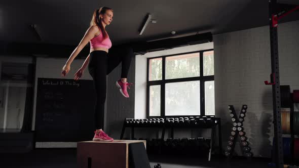 Woman athlete doing cardio exercise with lifting on pylo box in the gym.