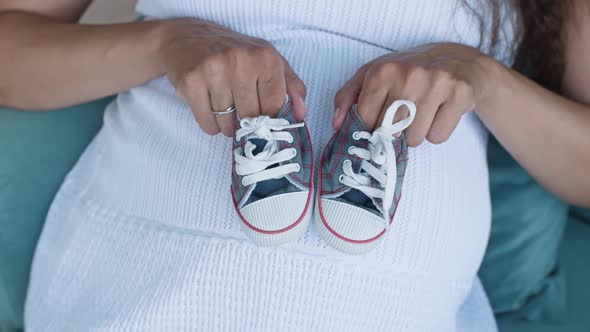 Pregnant Woman Holding Small Baby Shoes