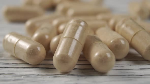 Pile of medical capsules on a wooden surface. 