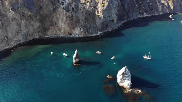 Aerial View of the Rocky Coast of the Bay with Detached Rocks and Boats with Tourists Swimming