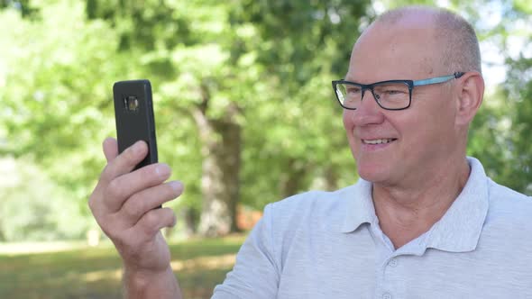 Face Of Happy Senior Man Using Phone At The Park