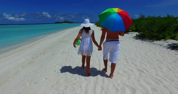 Young man and woman on honeymoon vacation live the dream on beach on clean white sand 4K background