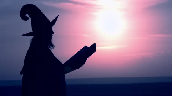 Woman in a Witch Costume Conjures Outdoors