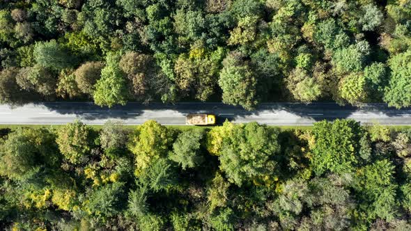 Autumn landscape from above with driving automobiles along a straight road through the countryside f