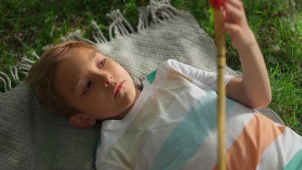 Closeup Upset Boy Examining Wooden Badminton Racket Lying Green Grass Alone