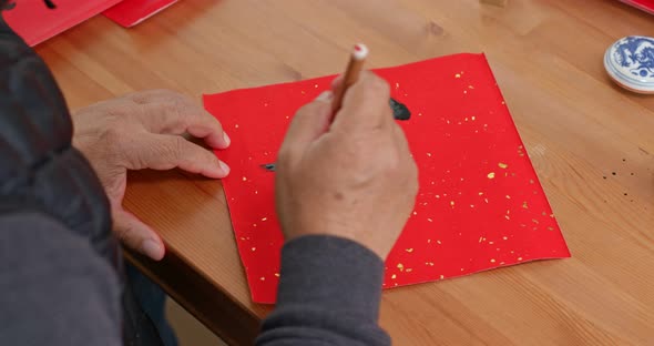 Man Write Chinese Calligraphy on Red Paper for Lunar New Year