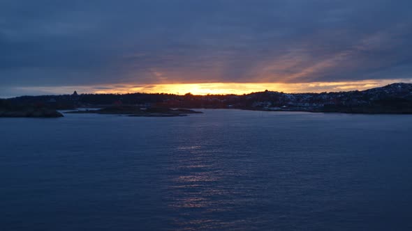 City Coastline From Ferry Travelling Across Ocean At Sunset