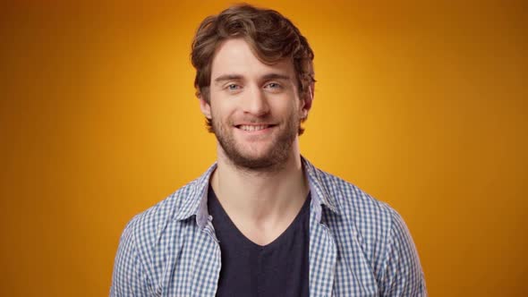 Portrait of Young Casual Bearded Man Smiling Against Yellow Background