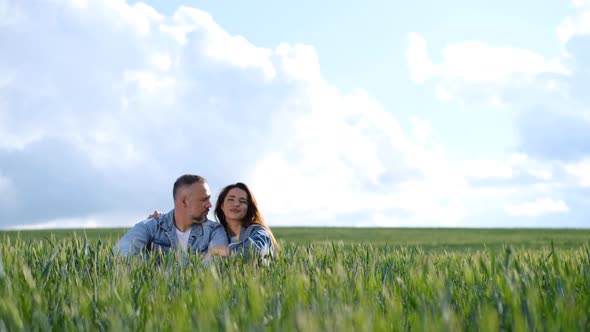 Loving Couple Resting Sitting in the Tall Green Grass in the Middle of the Field