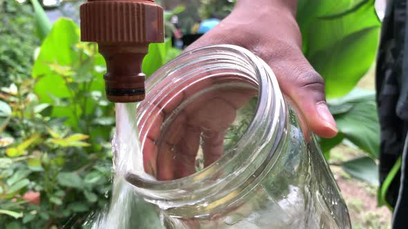 Filling glass jar with tap water