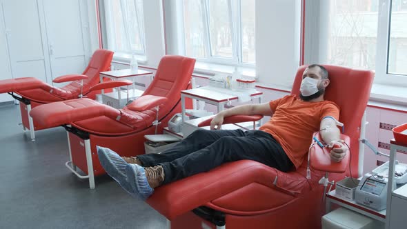 A Donor in a Mask Lies on a Couch. Man Donates Venous Blood. Blood Donation Concept