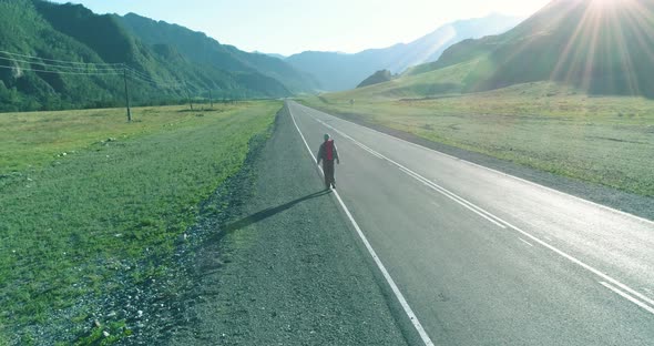 Flight Over Hitchhiker Tourist Walking on Asphalt Road