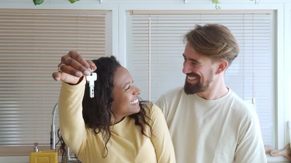 Smiling Multiethnic Heterosexual Couple Show the Keys to Their New House