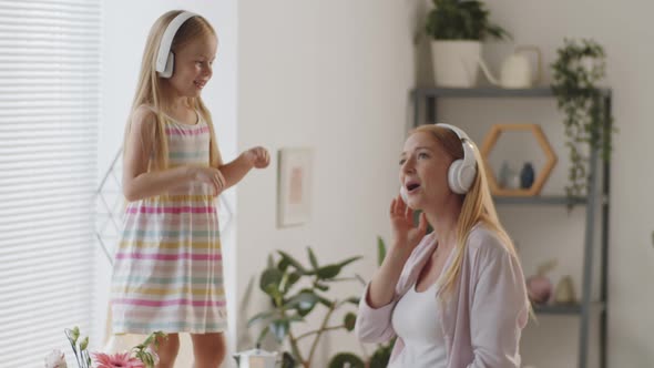 Pregnant Woman and Little Girl in Headphones Dancing and Singing