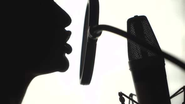 Silhouette of a woman singing a song in a recording studio. Black and White.