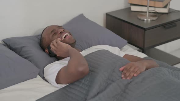 African Man Talking on Smartphone While Sleeping in Bed Close Up