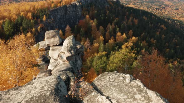 Aerial View of a Cliff Surrounded By a Colorful Autumn Forest at Sunset