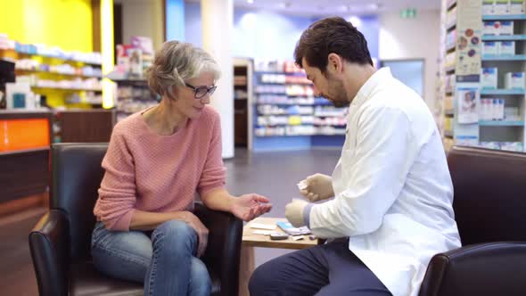 Pharmacist measuring blood sugar levels of diabetic customer