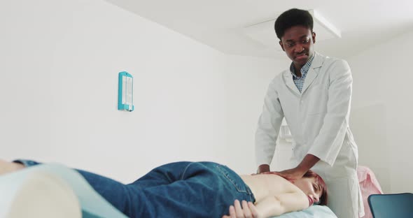 African Physiotherapist Conducts Massage Therapy To Young Female To Restore