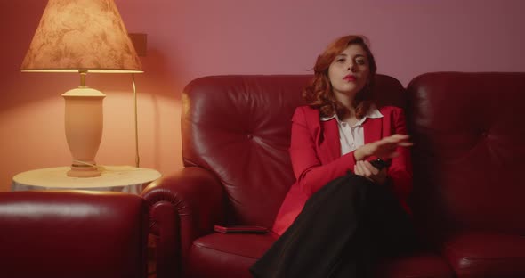 Beautiful girl with red jacket sitting on the sofa in the living room