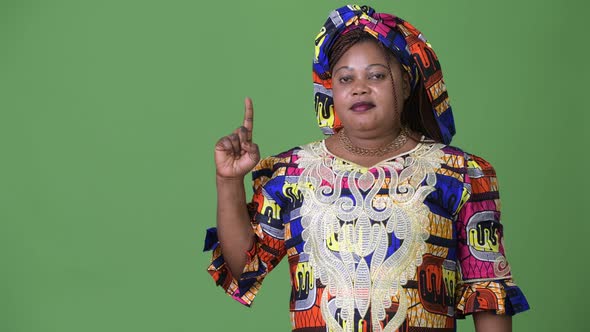 Overweight Beautiful African Woman Wearing Traditional Clothing Against Green Background