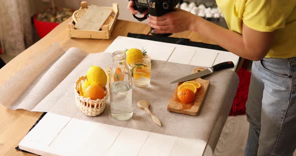 Woman food photographer take pictures with camera of fresh summer citrus lemonade drink