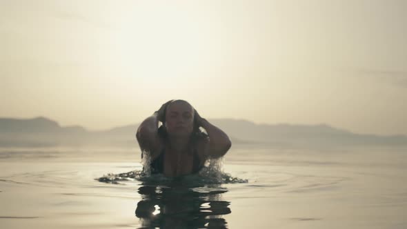 Slow Motion Video of a Girl After Swimming Raises Her Head From the Ocean Water