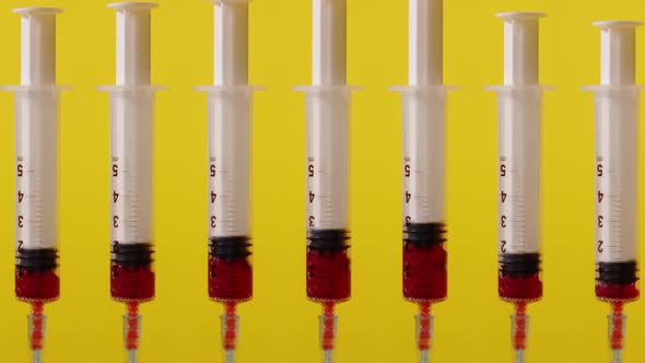 Many Syringes Fill with Blood on a Yellow Background