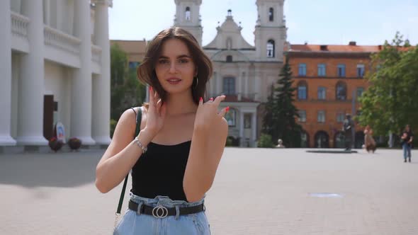 A beautiful Caucasian brunette girl walks on the street of the old town.