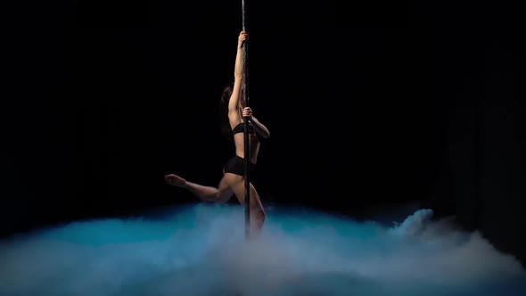 Girl with Flowing Hair Dancing on a Pole in a Dark Smoky Room, Black Background