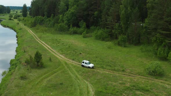 Aerial View of a Car Driving Along the River Bank