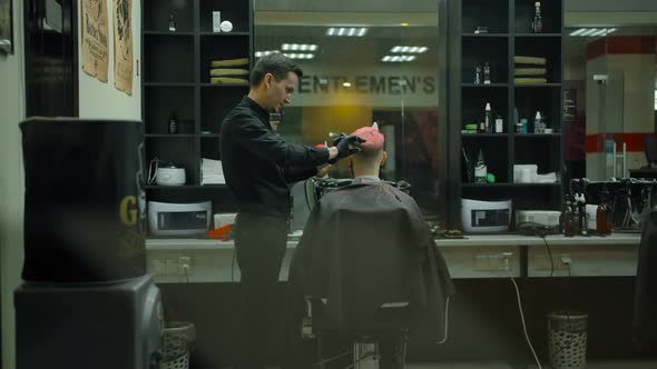 Wide Shot of Haircuts a Young Man with Colored Hair in a Barbershop