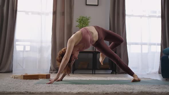 Flexible Trained Woman is Performing Yoga Asanas at Home Standing in Downwardfacing Dog Pose