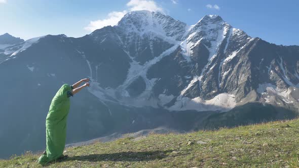 Funny Caterpillarlike Man Runs in a Sleeping Bag with His Arms Outstretched Against the Backdrop of