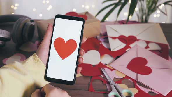 Young Female Hand Holding Smartphone with Red Heart on a Screen