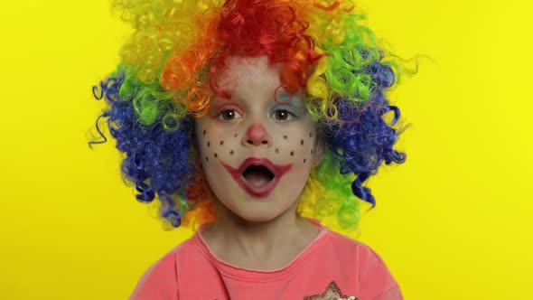 Little Child Girl Clown in Wig Making Silly Faces. Fool Around, Singing, Showing Tongue. Halloween