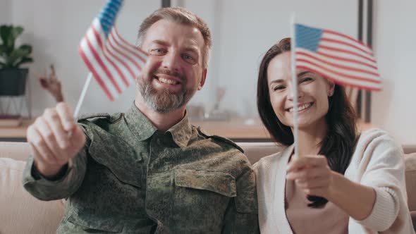 Military Man and his Wife Waving American Flags