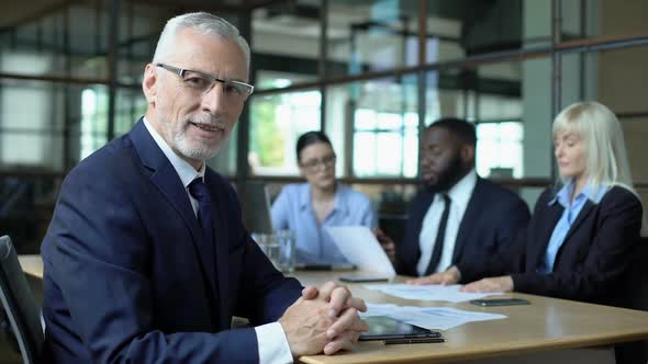 Elderly Company Director Looking Camera, Office Colleagues Discussing Strategy