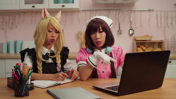 Lovely Asian Female Cosplayers with Laptop Planning Cosplay Performance at Home