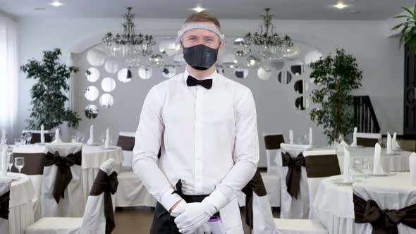 A Male Waitress Wearing a Face Mask and with an Infrared Thermometer for Her Forehead to Check Her
