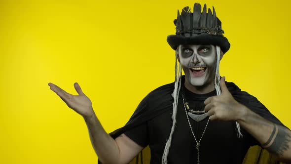 Sinister Man with Horrible Halloween Skeleton Makeup Trying To Scare, Pointing To the Left