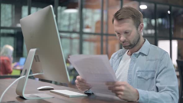 Creative Young Man Studying Documents at Work