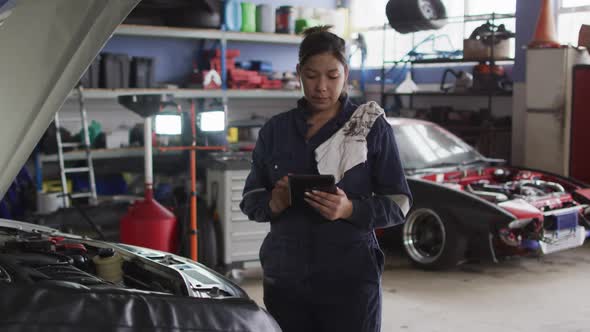 Portrait of female mechanic using digital tablet and smiling at a car service station